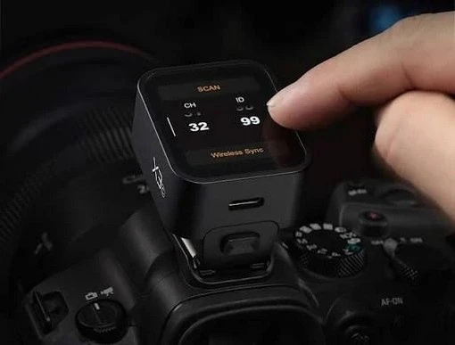 Палець торкається сенсорного OLED-екрана радіосинхронізатора Godox X3 на камері в гарячому башмаку